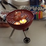 a small round grill with hot dogs on it
