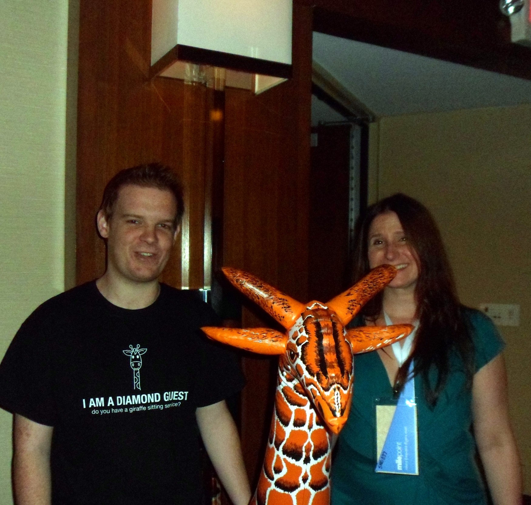 a man and woman standing next to a giraffe