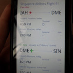 a hand holding a phone with a flight schedule