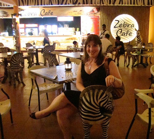 a woman sitting in a restaurant with a zebra sculpture