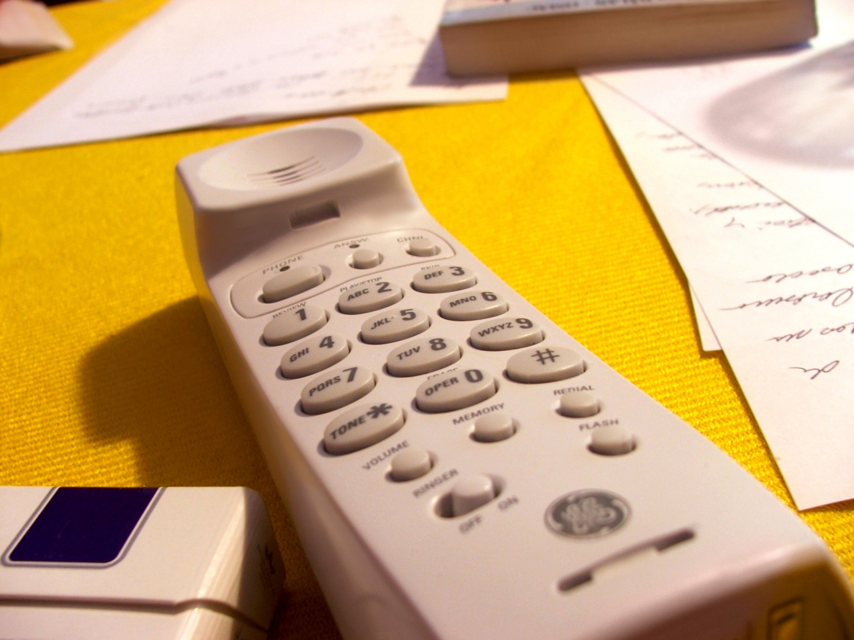 a white cordless phone on a yellow surface