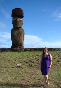 a woman standing in front of a large statue with Easter Island in the background