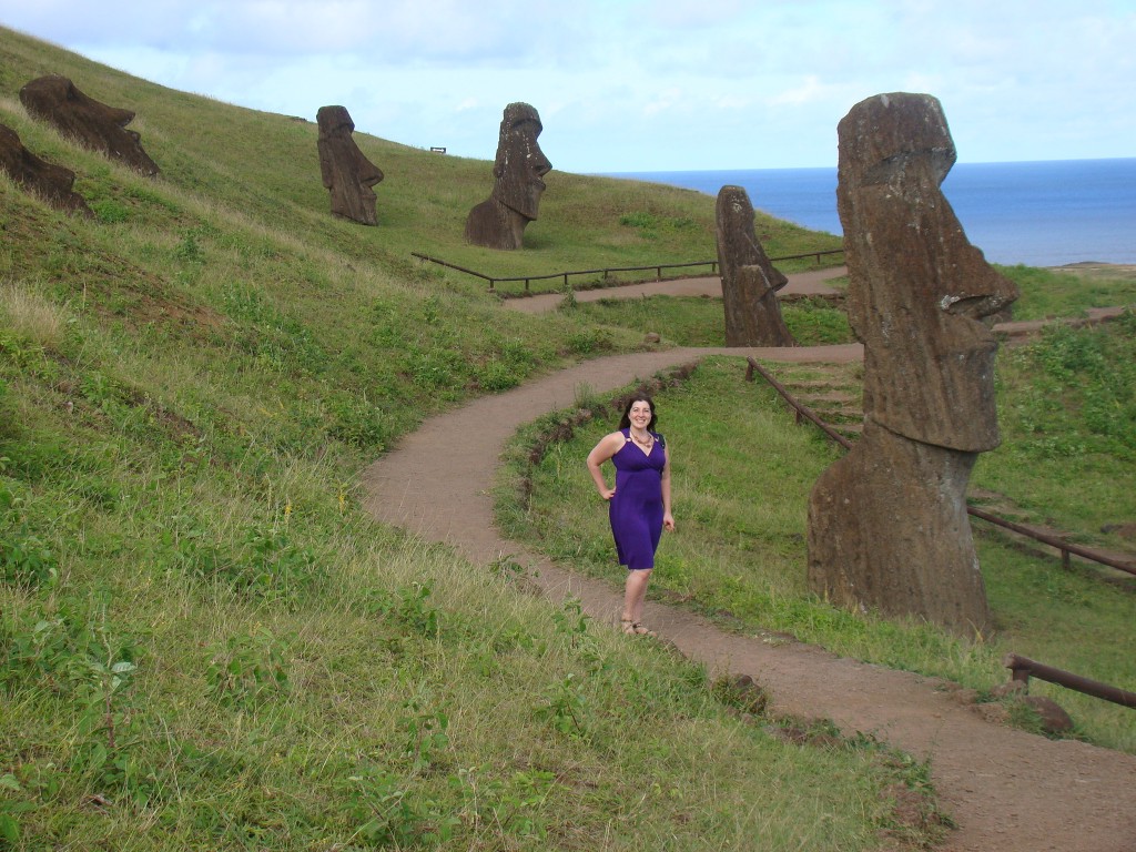 a woman standing on a path with statues on the side