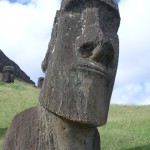 a stone statue of a man with Easter Island in the background