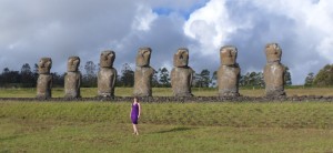 a woman standing in a field with several large statues