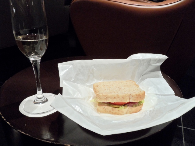 a sandwich on a paper wrapper next to a glass of champagne