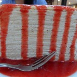 a piece of cake with red sauce on a plate