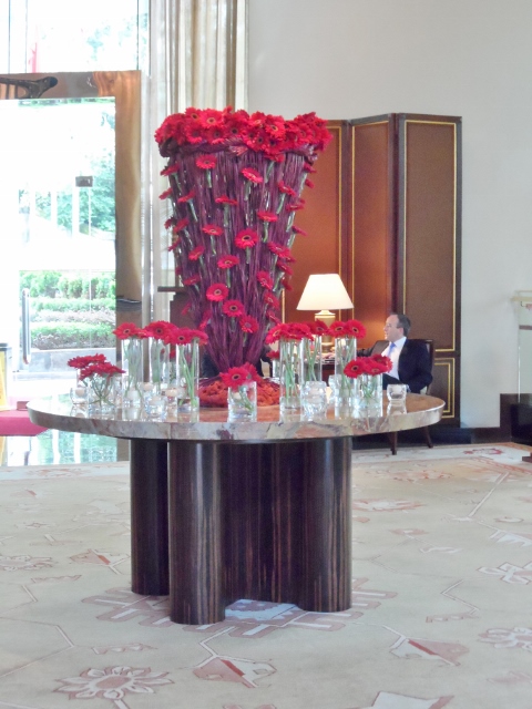 a large vase of red flowers on a table