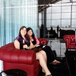 two women sitting on a red couch