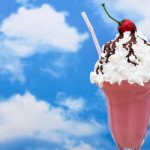 a pink milkshake with whipped cream and cherry on top