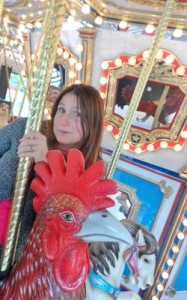 a woman standing next to a carousel