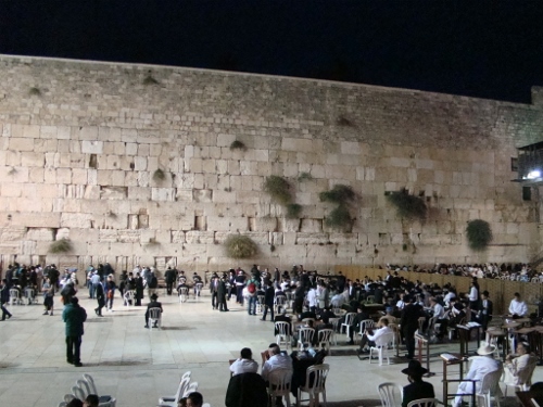 a group of people sitting in chairs outside a stone wall with Western Wall in the background