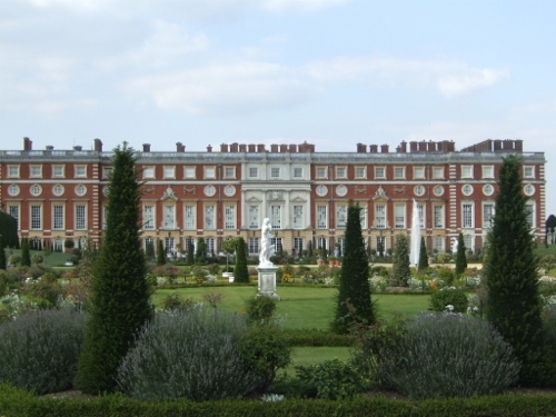 a large building with a garden with Hampton Court Palace in the background