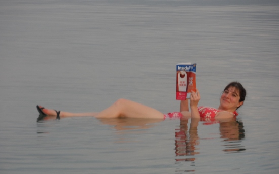 a woman lying in water holding a book