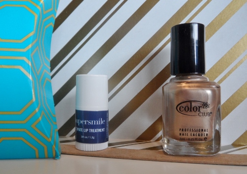 a bottle of nail polish next to a small white and blue bag