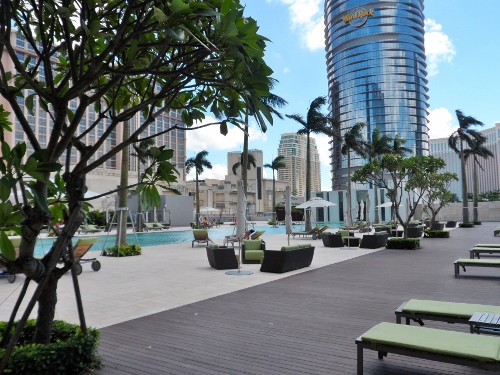 a pool with lounge chairs and trees in front of a skyscraper