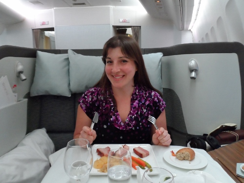 a woman sitting at a table with food and glasses