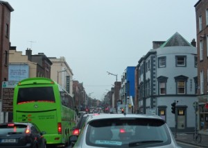 a green bus and cars on a street