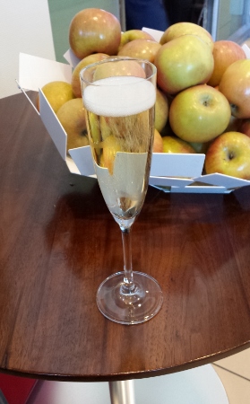 a glass of champagne next to a basket of apples