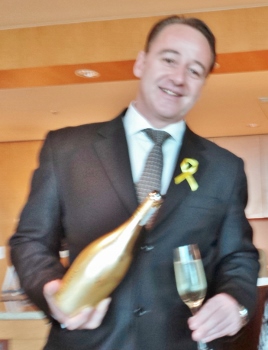 a man in a suit holding a champagne bottle and a glass