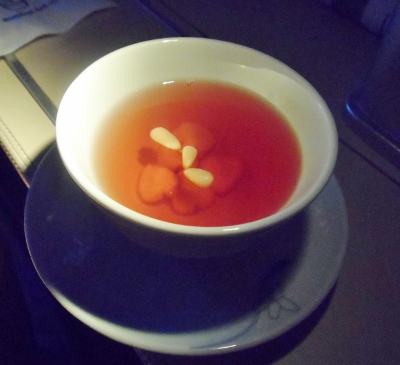 a cup of liquid with red liquid and white objects on a plate