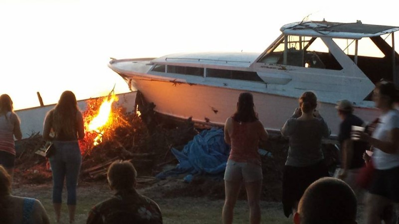 a group of people watching a boat that is on fire