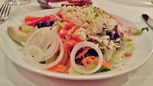 a plate of salad with onions and cheese