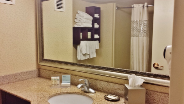 a bathroom mirror with a sink and towels