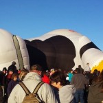 a large group of people standing around a giant inflatable cow