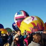 a group of people standing in front of hot air balloons