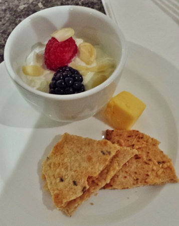 a bowl of food with fruit and cheese on a plate
