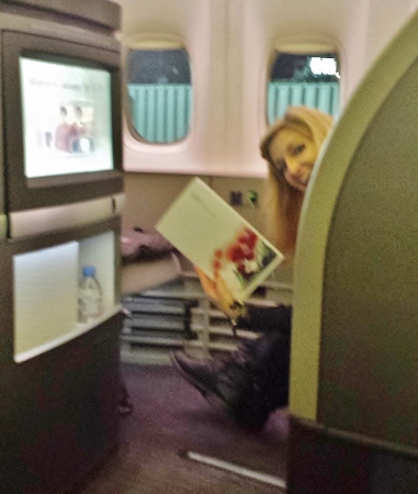 a woman sitting in an airplane with a book