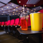 a cup and drink on a tray in a movie theater