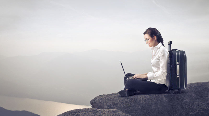a woman sitting on a rock with a laptop