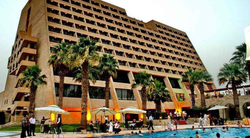 a large building with palm trees and people in front of it