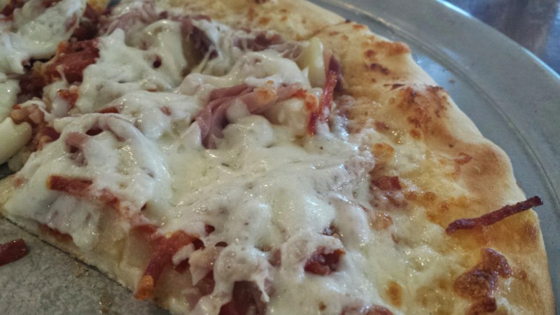 a pizza with cheese and ham on a plate