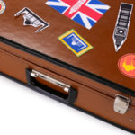 a brown suitcase with stickers on it