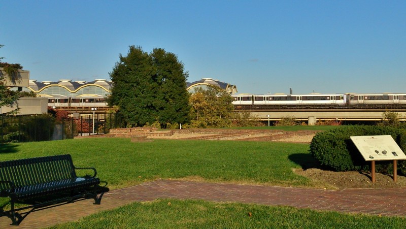 a park with a bench and a train in the background
