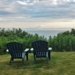 two chairs in a grassy area with a body of water in the background