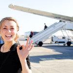 a woman making a hand gesture in front of an airplane