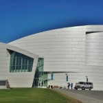 a white building with a curved roof with University of Alaska Museum of the North in the background