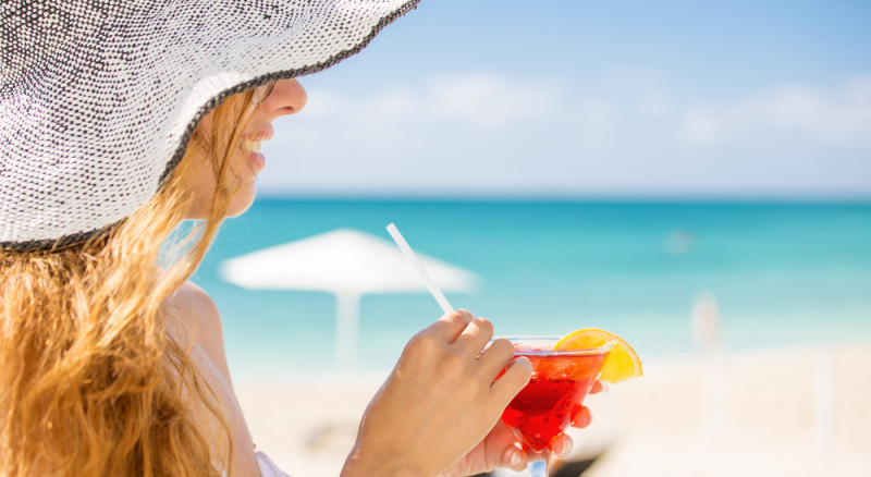 a woman holding a drink on a beach