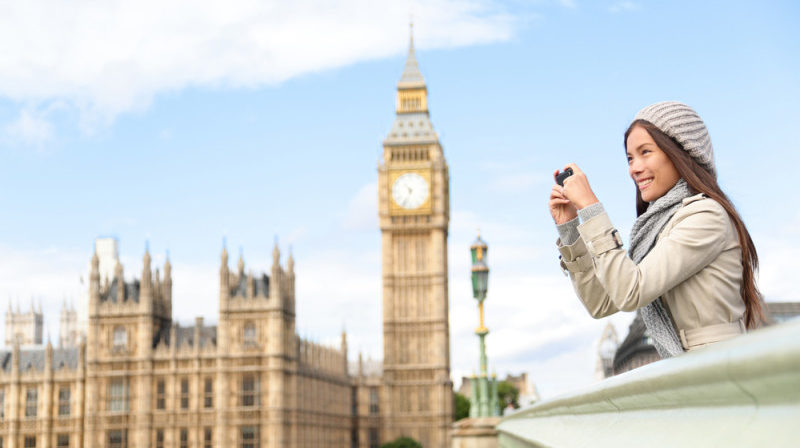 a woman taking a picture of a clock tower