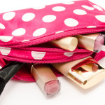 a pink polka dot makeup bag with makeup brushes and lipstick