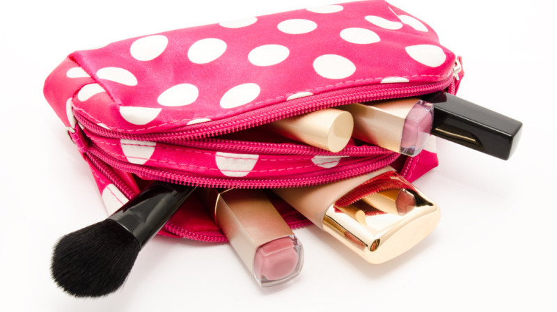 a pink polka dot makeup bag with makeup brushes and lipstick