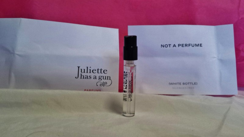 a small bottle of perfume next to white bags