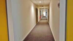 a long hallway with doors and a fire extinguisher