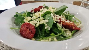 a plate of salad with cheese and tomatoes
