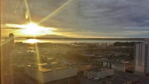 a sun shining through the clouds over a city