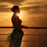 a woman leaning on a railing at sunset